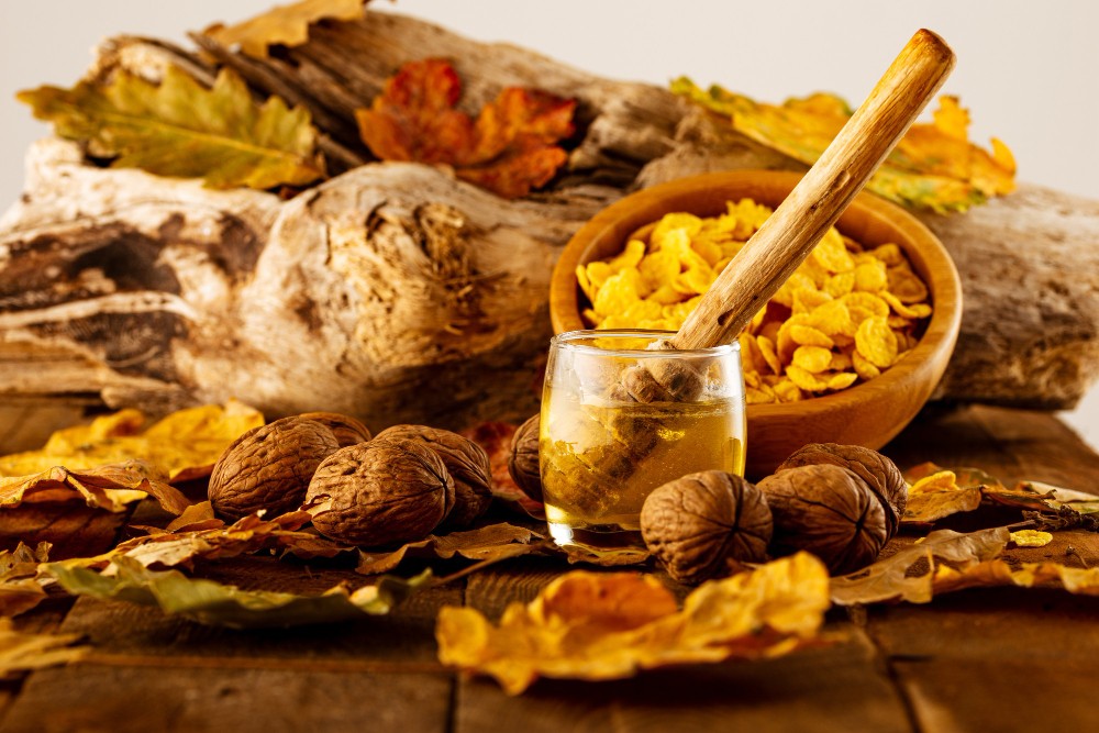 Noix, miel et feuilles d'automne sur une table en bois.