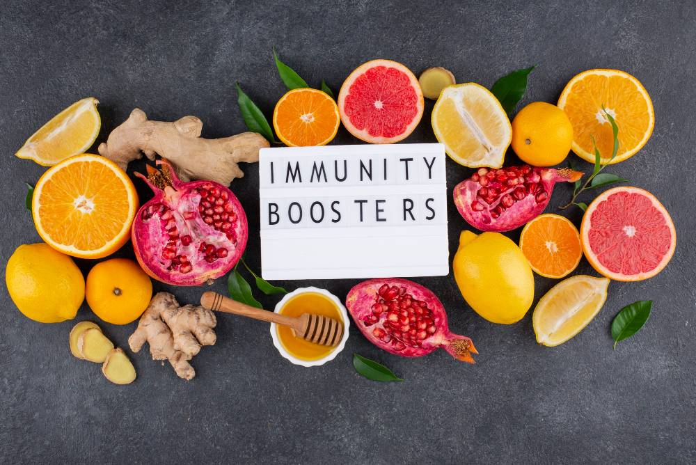 Fruits, gingembre, miel et panneau "Immunity Boosters" sur fond gris.