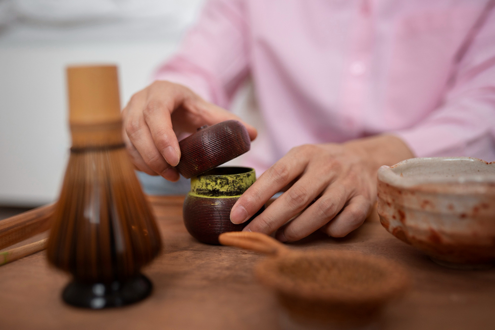 Personne ouvrant un pot de thé matcha sur une table en bois.