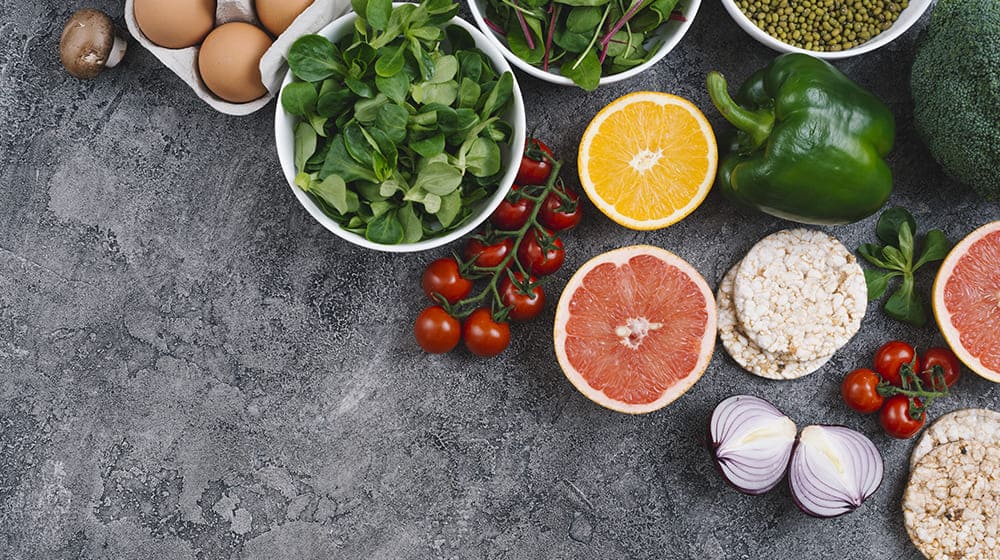 Assortiment de légumes, fruits et céréales sur une table en pierre.