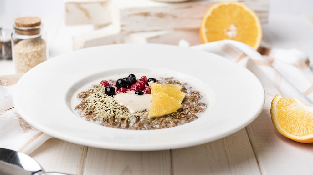 Bol de céréales avec fruits rouges et tranches d'orange.