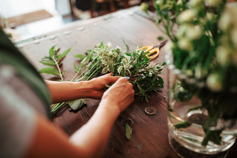 Personne arrangeant des herbes fraîches sur une table en bois.
