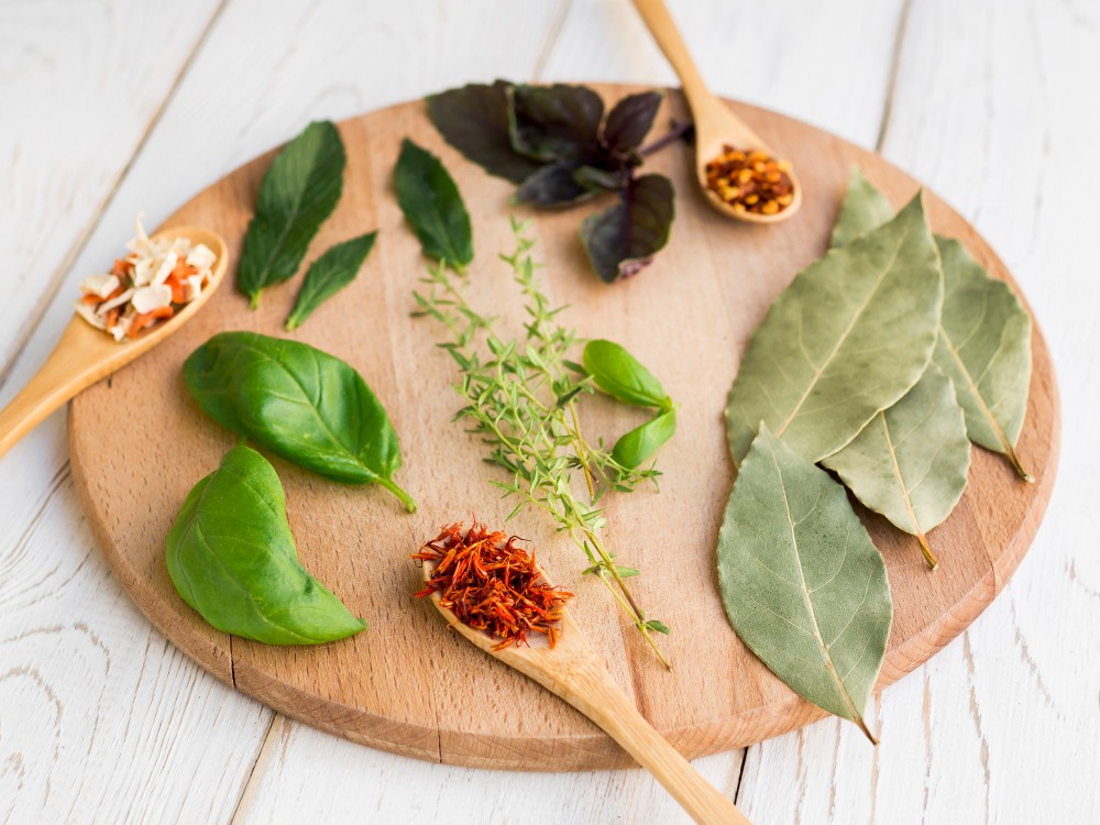 Assortiment d'herbes et épices sur une planche en bois.
