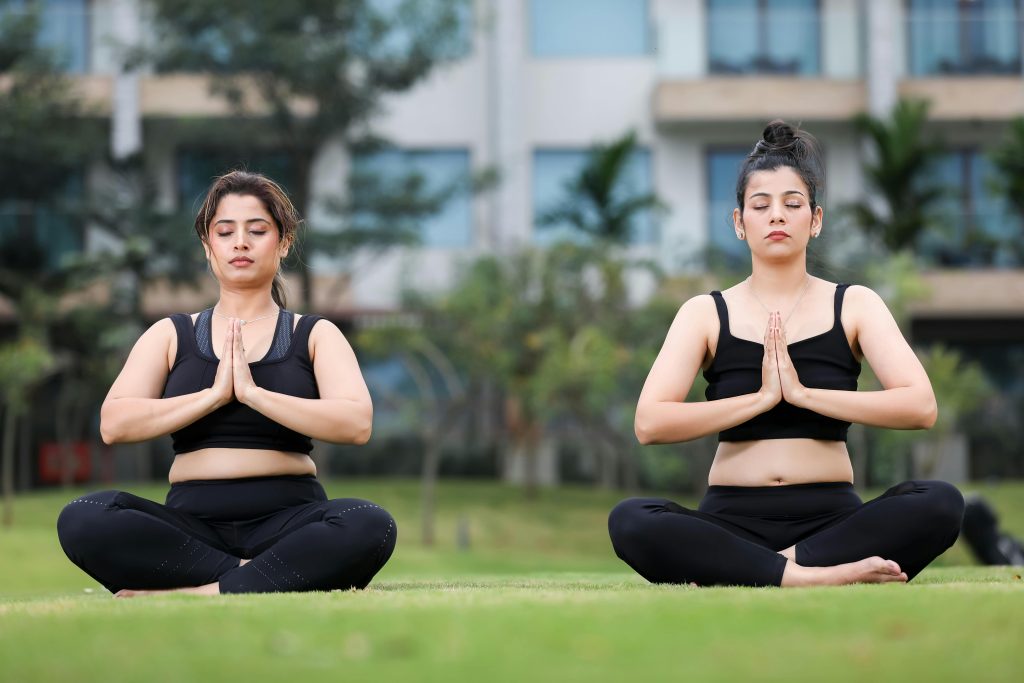 Deux femmes méditent en position du lotus dans un parc.