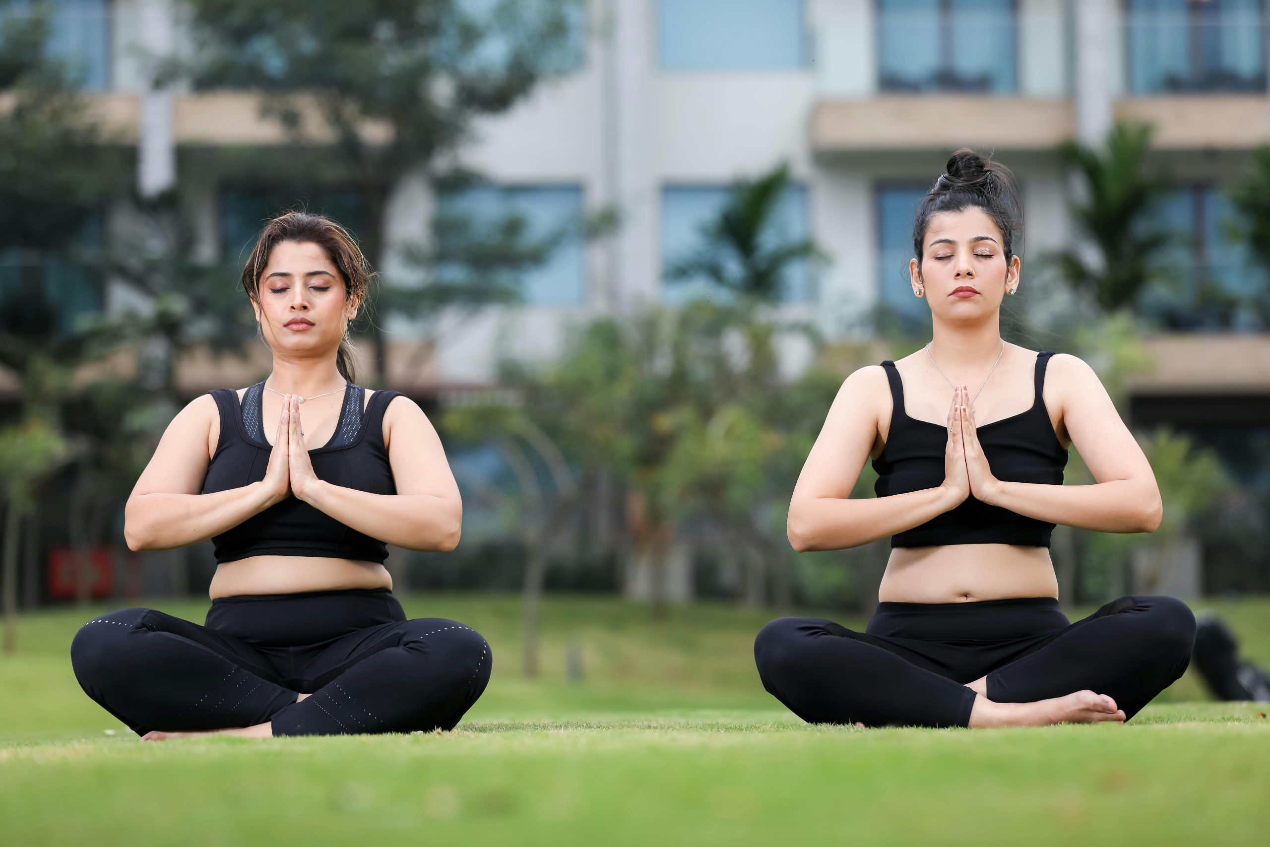 Deux femmes méditent en position du lotus dans un parc.