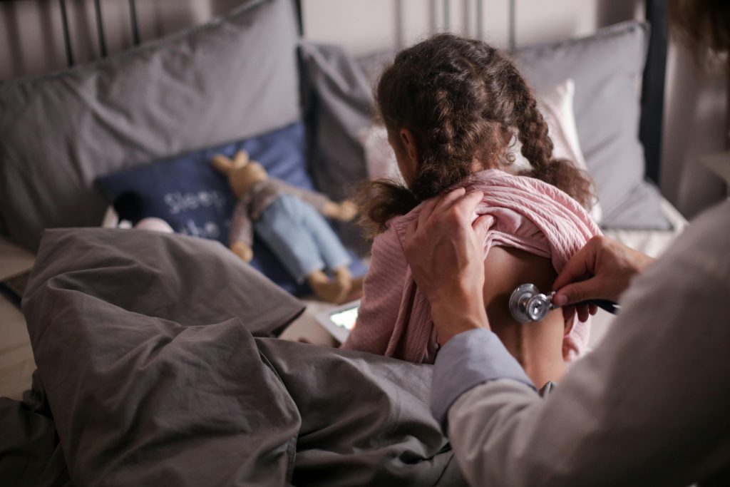 Enfant examinée par un médecin avec un stéthoscope sur un lit.