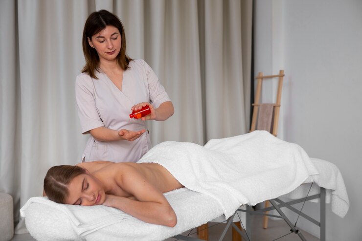 Femme recevant un massage, masseuse appliquant de l'huile, sur une table de massage.