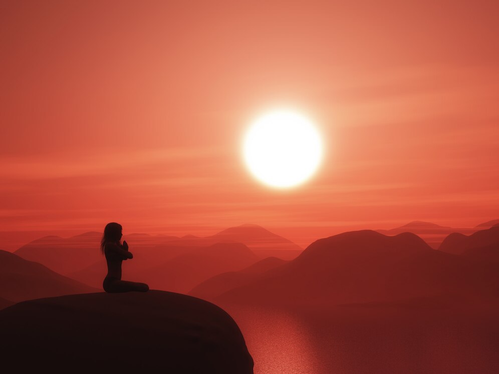 Personne méditant au coucher du soleil sur une montagne rougeoyante.