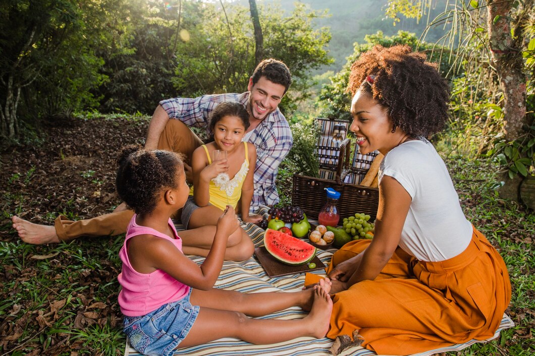 Famille profitant d'un pique-nique en plein air avec des fruits et boissons.